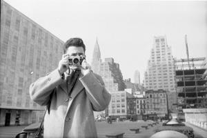 Bob Lerner for LOOK magazine, Hungarian Refugee [Man with a camera standing with his back to the United Nations Building], January 31, 1957, Museum of the City of New York. Gift of Cowles Magazines, Inc, X2011.4.7087-57