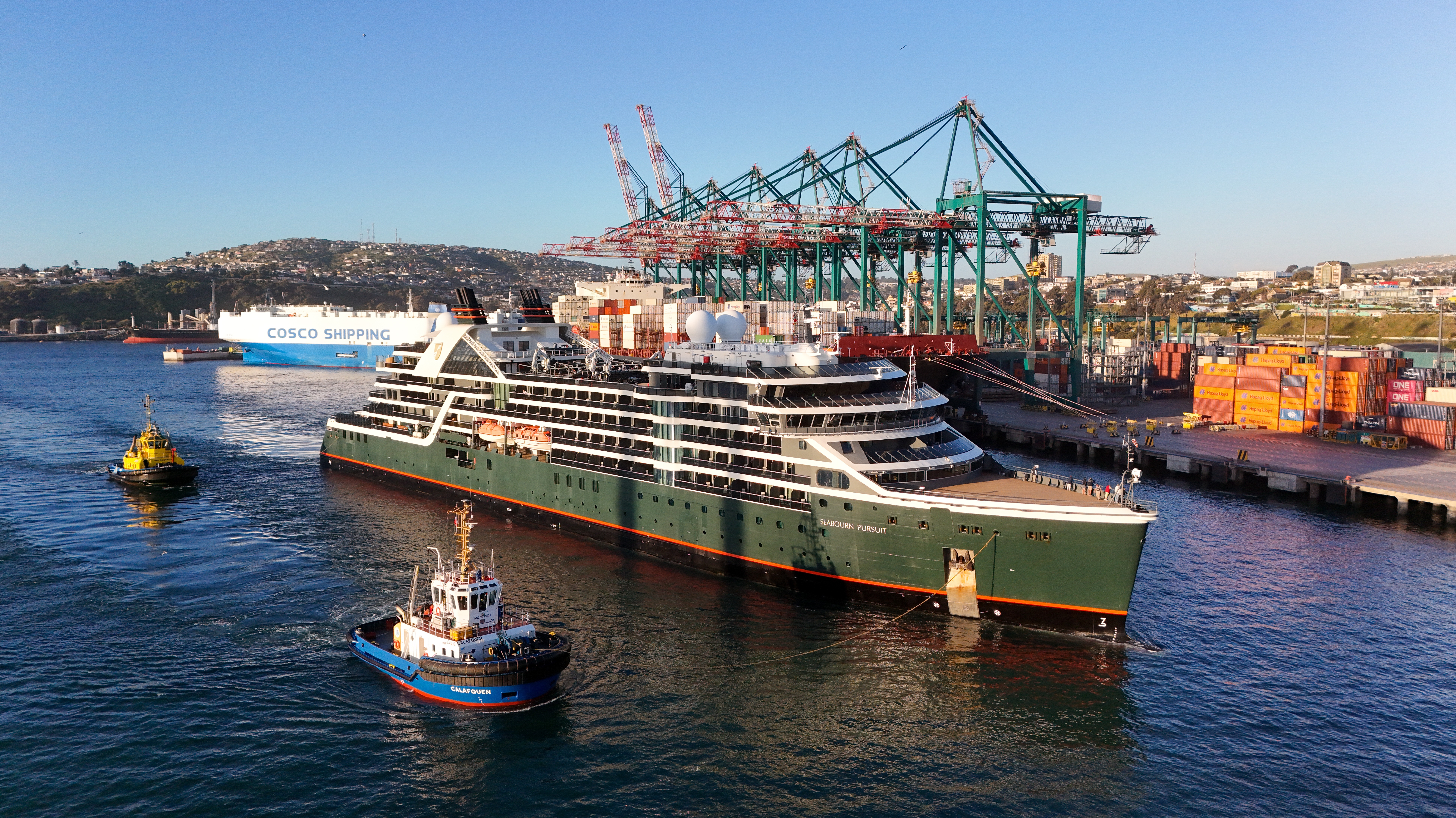 Aerial view of the Seabourn Pursuit cruise ship being guided into DP World’s San Antonio Terminal in Chile, with container cranes in the background.