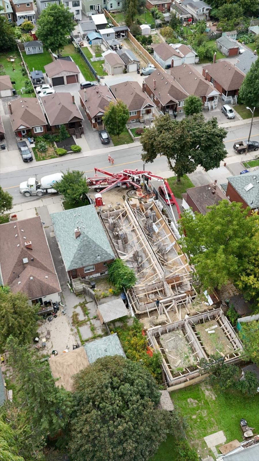 Aerial view of an active concrete pour at TUK Group's Lambton project in Toronto. A concrete pump and mixer truck sit on the street while crews place the foundation walls for the 10-unit rental building on a mid-block lot between existing homes. The site shows the project's scale relative to the surrounding residential street, illustrating TUK Group's approach of adding purpose-built rental homes within established Toronto neighbourhoods.