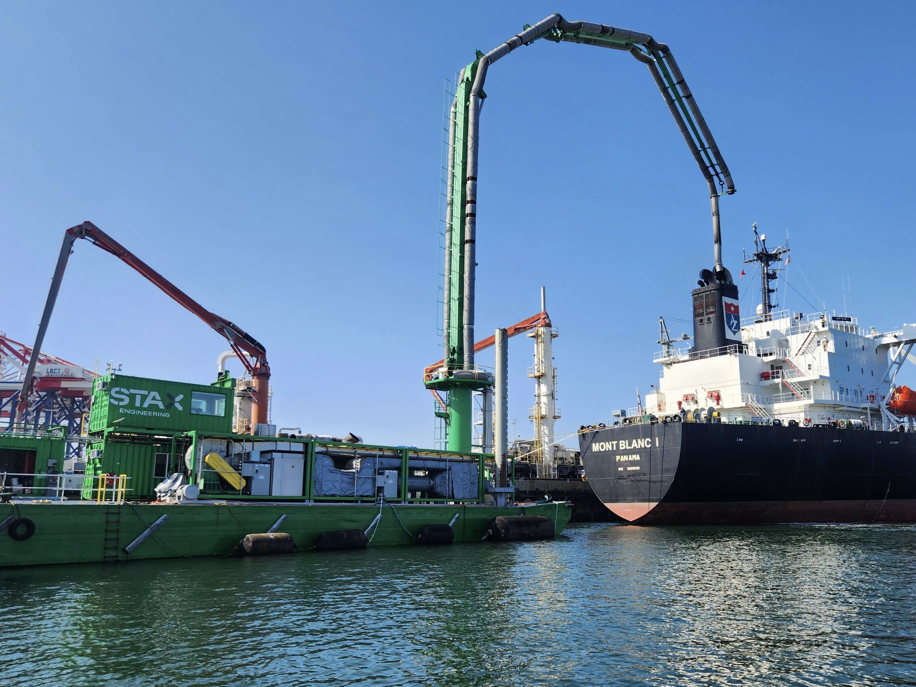 green STAX barge with large boom connecting to the auxiliary exhaust pipes of a tanker ship