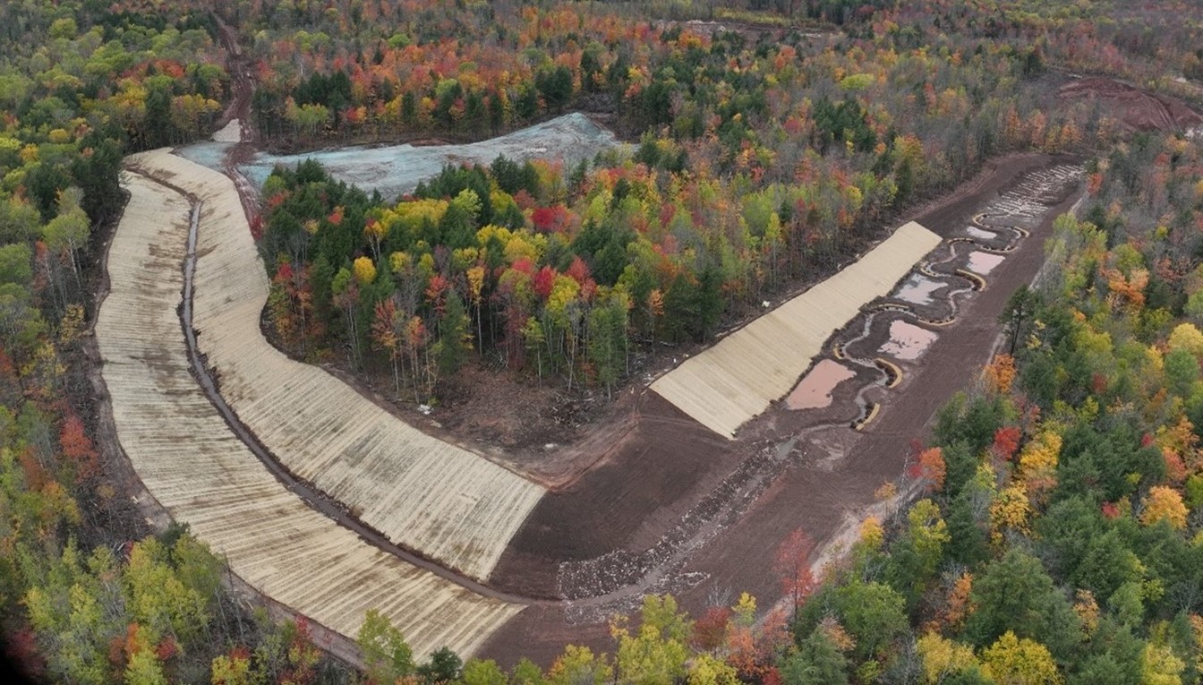 East stream diversion to divert water around future site infrastructure. Note the wetland mitigation construction within the stream diversion / mitigation area and the hydroseeded former wetland in the background.