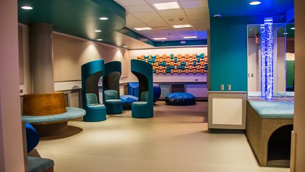 The suite includes a calming transition foyer, a family room, individual rooms with bubble tubes, and an adult area (all fully soundproof). The space also includes an airplane experience and a bathroom available to the public which includes an adult changing table and adjustable sink.