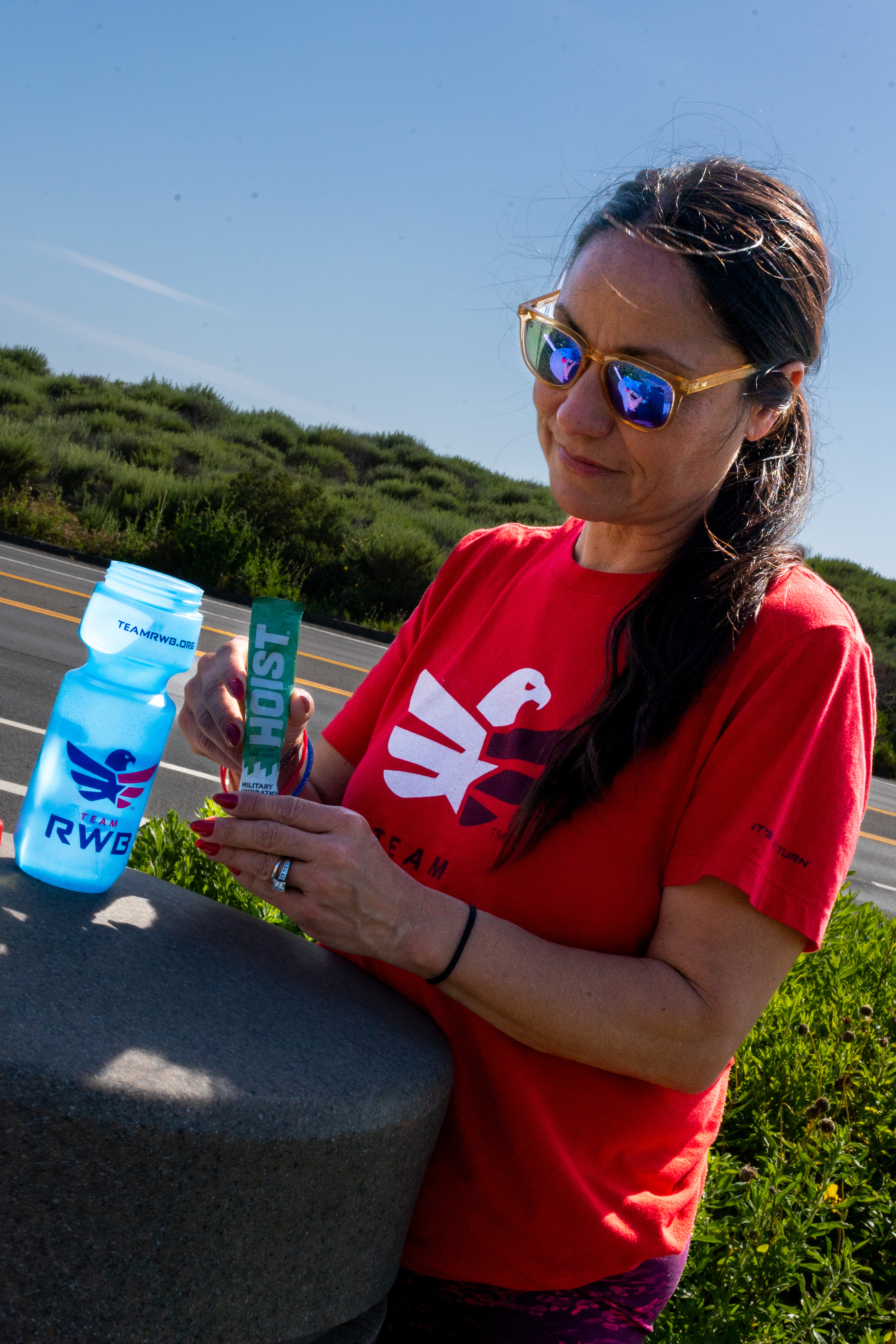 A Team Red, White and Blue member pours a HOIST stick pack into a water bottle