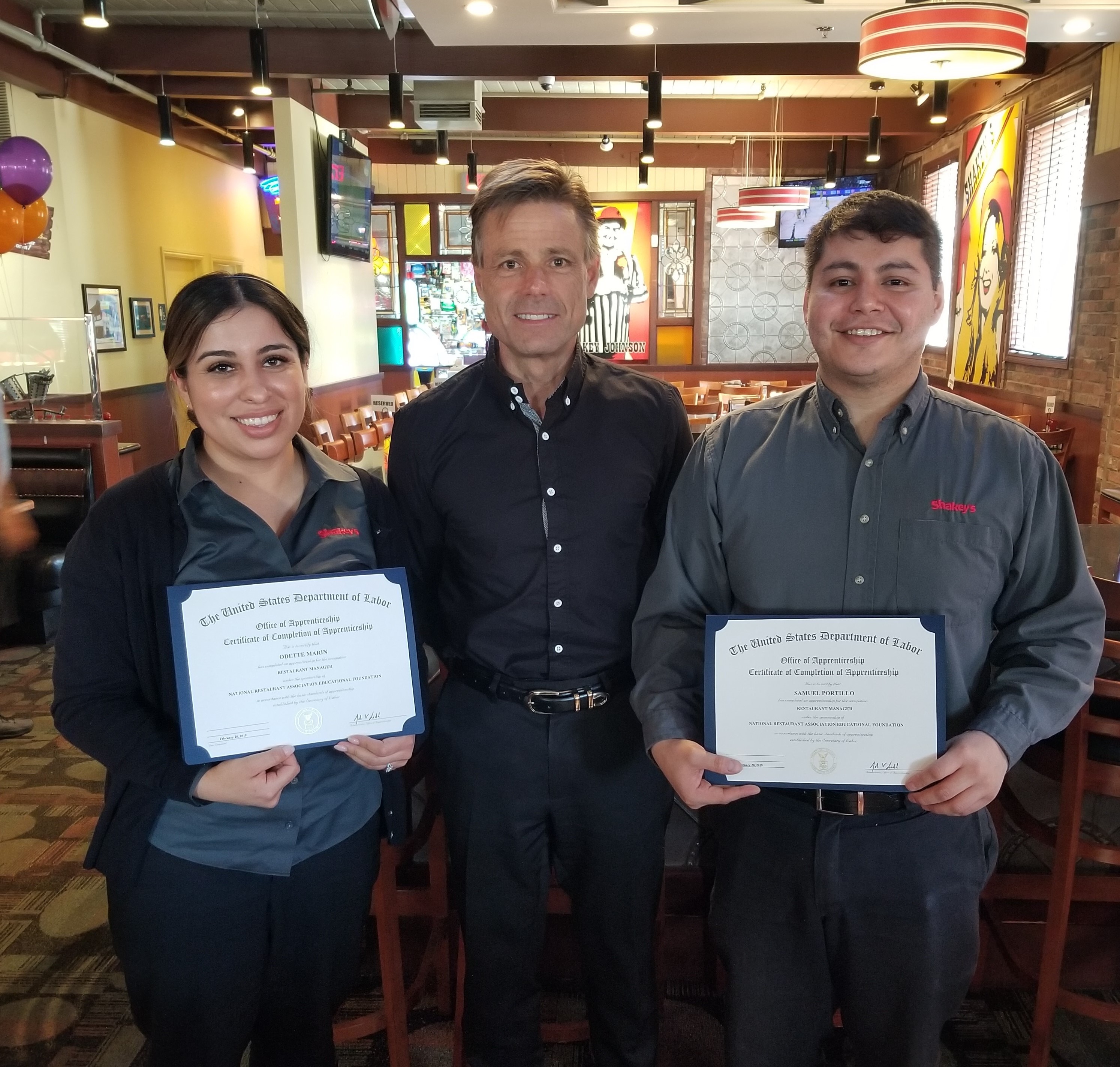 Nick Mayer, CEO of Shakey’s USA, Inc., with Odette Marin and Samuel Portillo, the first restaurant management apprentices to complete the national program.