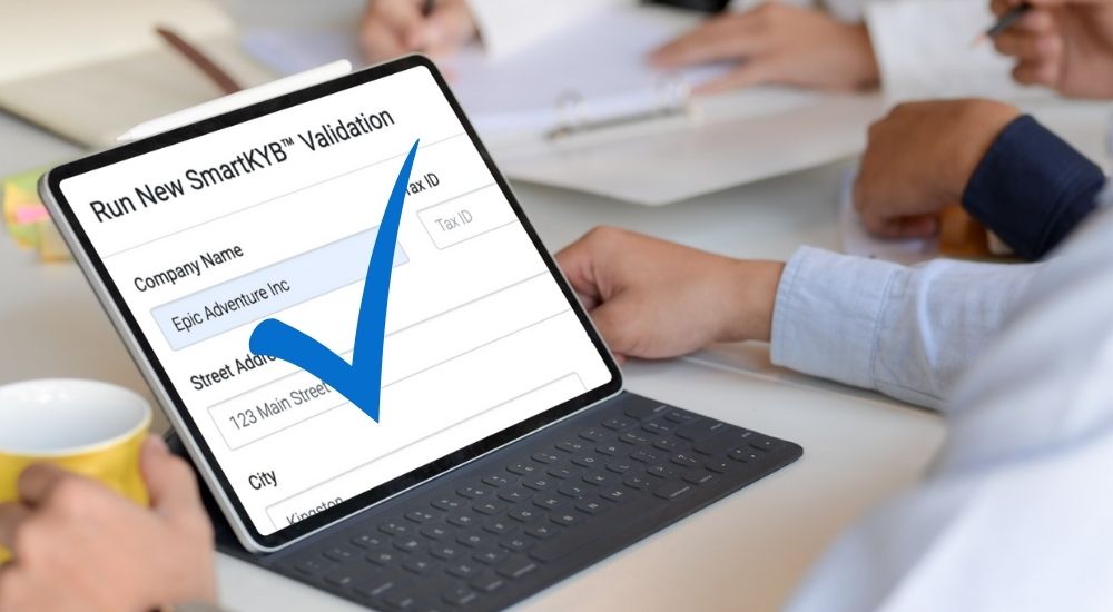 Person using a tablet to run a SmartKYB™ validation, with a large blue checkmark indicating approval.