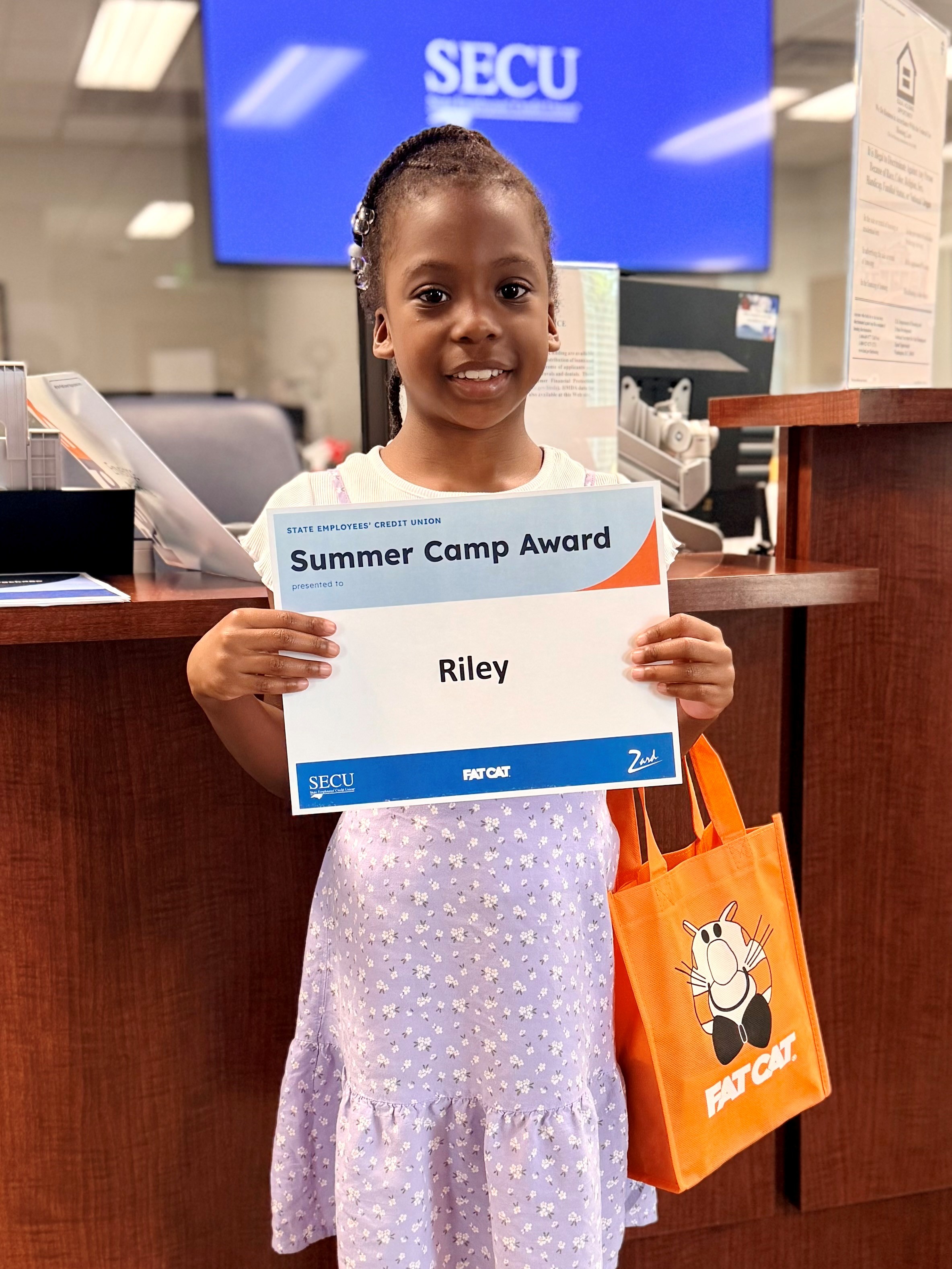 Riley Hines accepts her $500 Summer Camp Award from the Greenville-First Street Branch.