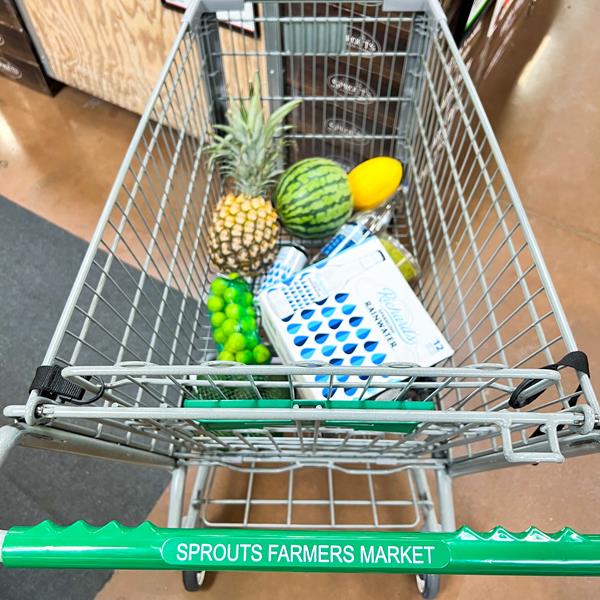 A case of Richard's Rainwater sparkling water bottles in a cart from Sprouts Farmers Market with other fruit