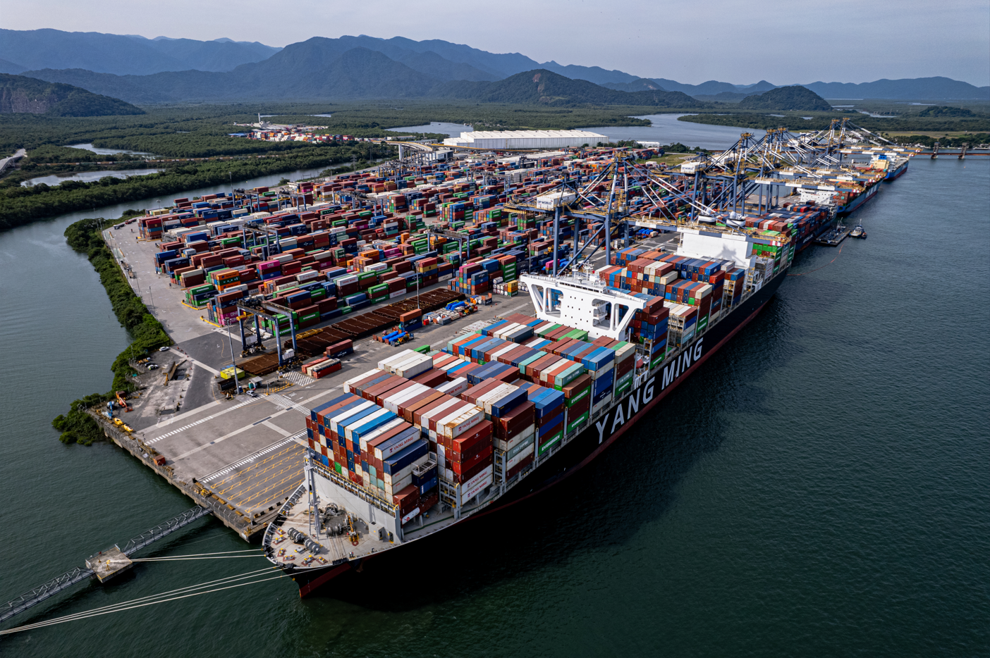 Aerial view of DP World's container terminal at the Port of Santos, Brazil, with a container ship berthed alongside the quay.