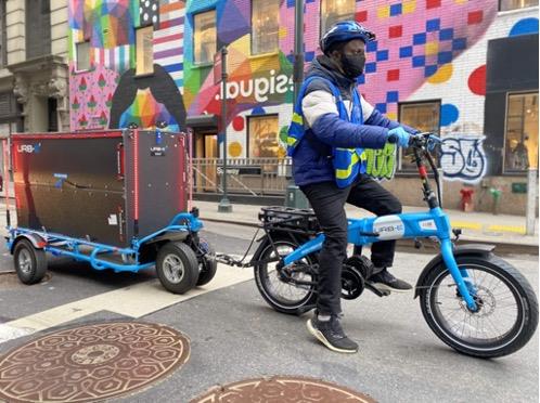 An URB-E e-bike driver delivers AxleHire's goods using their micro-container delivery systems through the streets of New York City. 