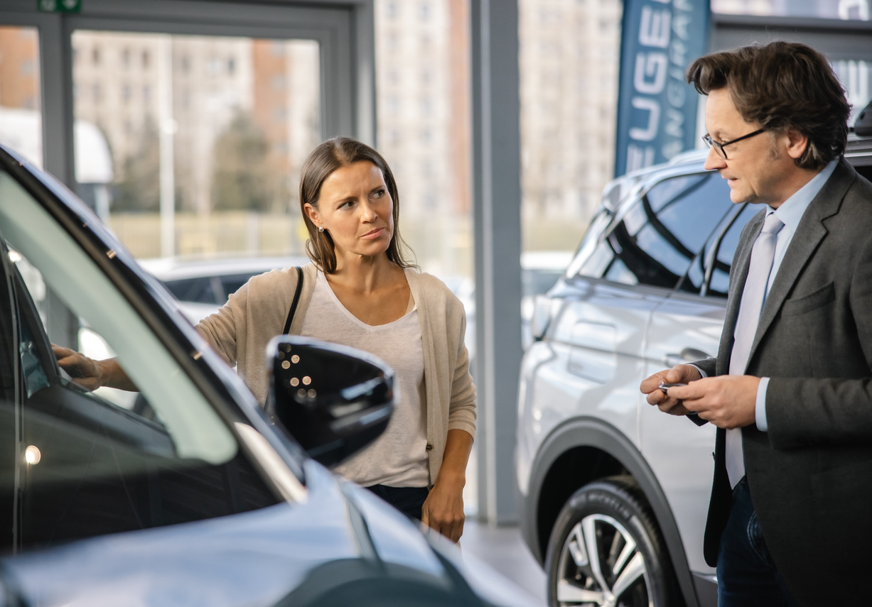 A customer discussing vehicle pricing with a sales representative at a car dealership