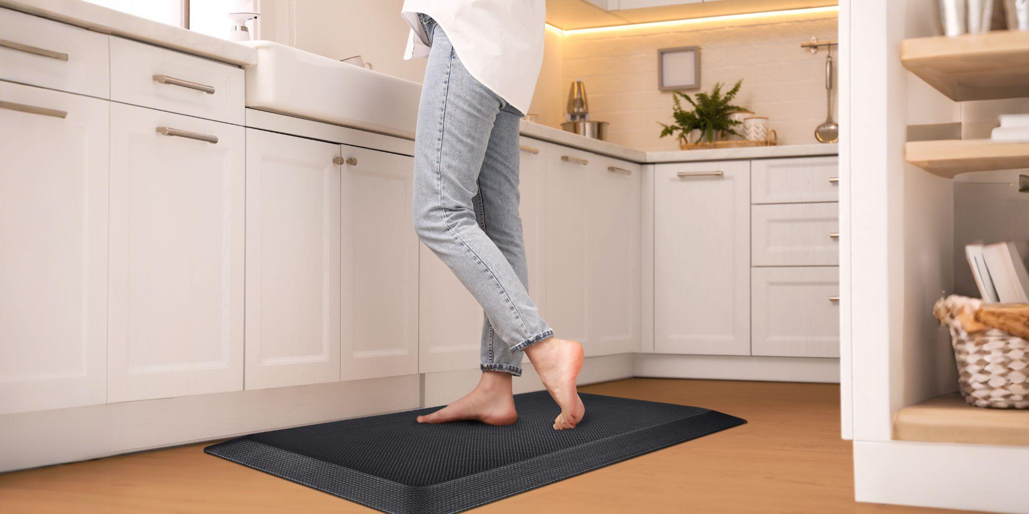 User standing barefoot on a FEATOL anti fatigue mat in a kitchen for everyday comfort.