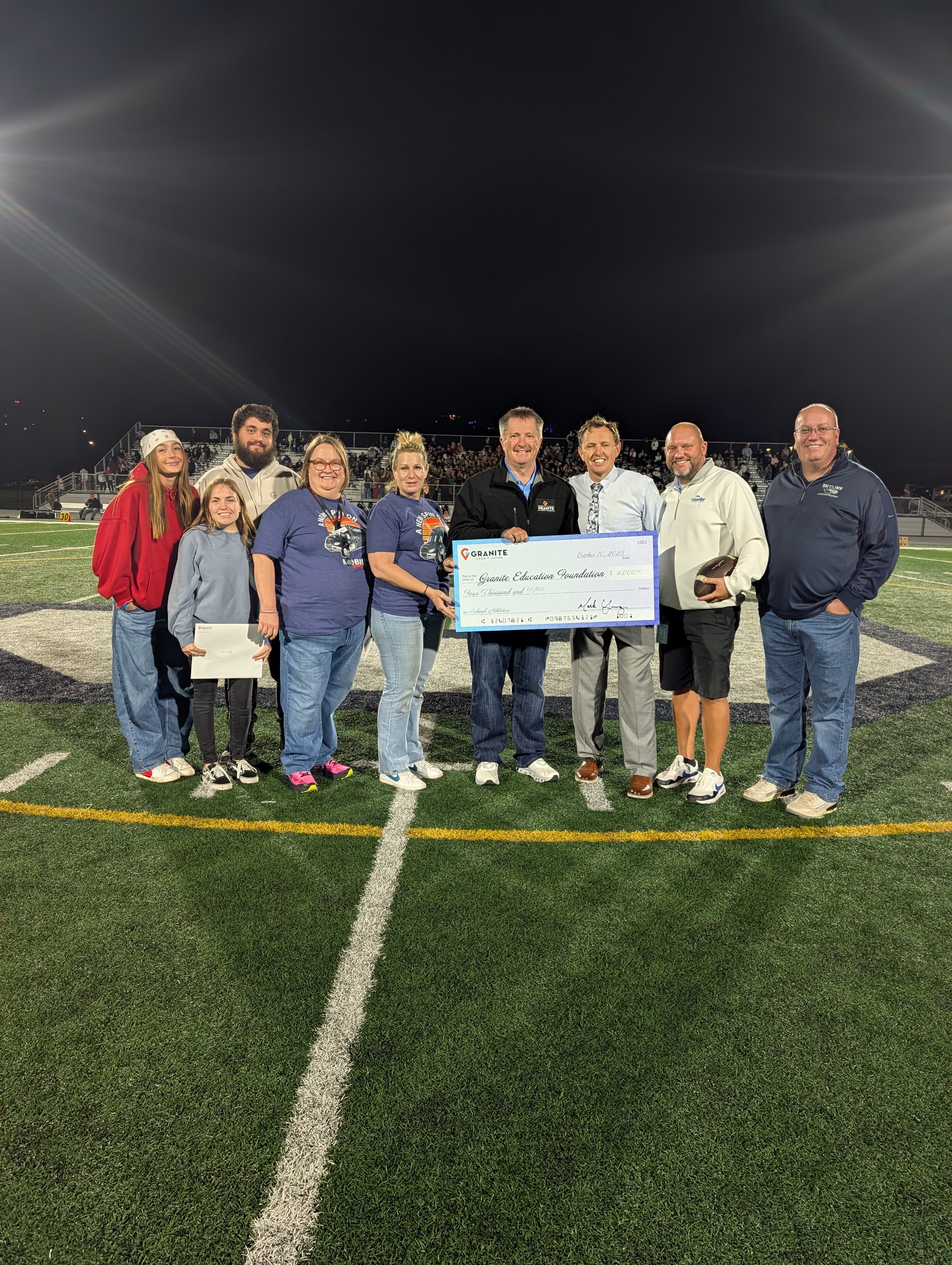 Granite Credit Union donates $4,000 to the Granite Education Foundation: CEO Mark Young presents the $4,000 donation to Superintendent Ben Horsley of the Granite School District and Jadee Talbot, chief executive officer of the Granite Education Foundation during senior night at Skyline High School