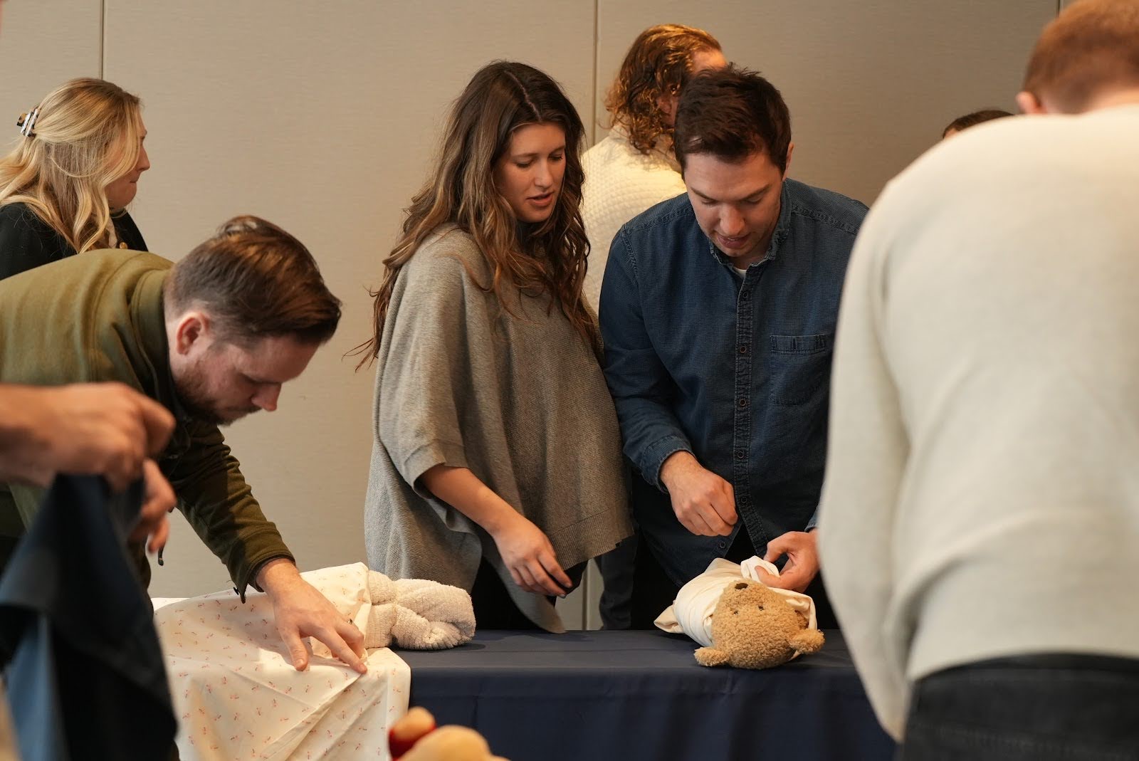 Parents learning newborn care techniques with practice dolls at an Expecting Together prenatal class in Chicago.