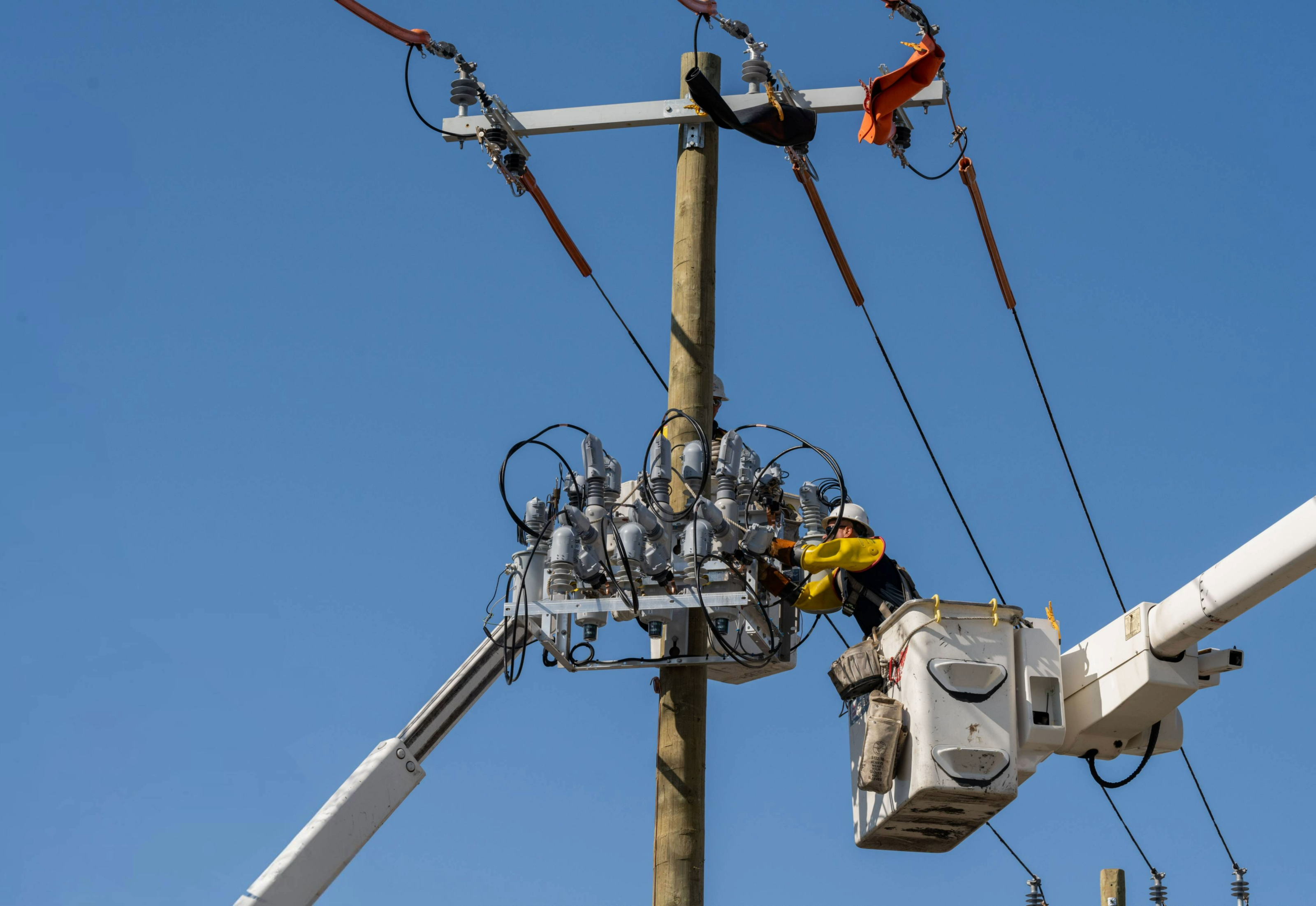 Overhead crew installing a recloser on a new power pole