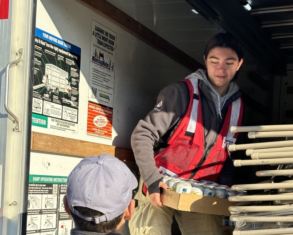 An AmeriCorps member serving with American Red Cross moves food and supplies off a truck.