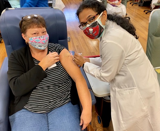 Florida Cancer Specialists medical oncologist Mamta Choksi, MD administers a COVID-19 vaccine to a patient.