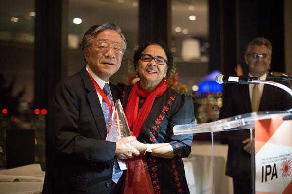 Dr. Harubumi Kato (left) receiving his Gold Medal award from IPA Past-President, Dr. Tayyaba Hassan (right), and IPA President, Dr. Luis Arnaut (background)