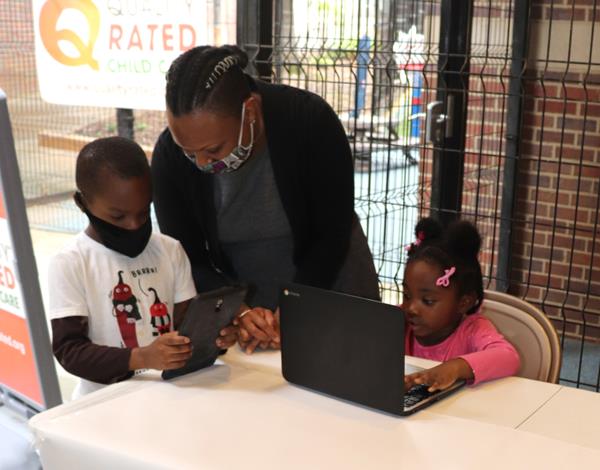 Atlanta Children’s Shelter (ACS) children using digital learning devices  provided by LogistiCare (left to right): Clayshaun, previous ACS kindergarten student; Aseelah Williams, Development Coordinator, ACS; Queen, ACS kindergarten student.