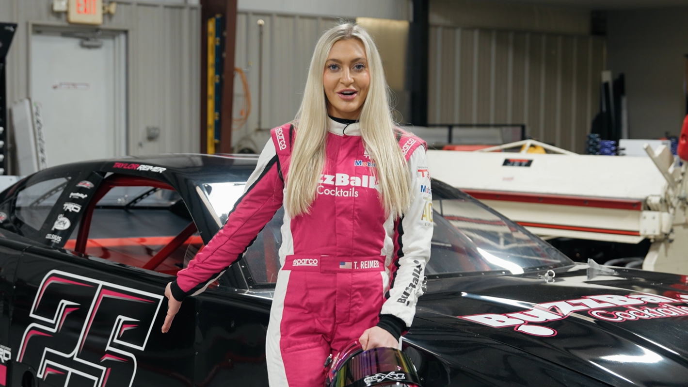 Reimer, wearing her pink BuzzBallz racing suit, stands in front of her ARCA series BuzzBallz race car as she promotes responsible drinking.