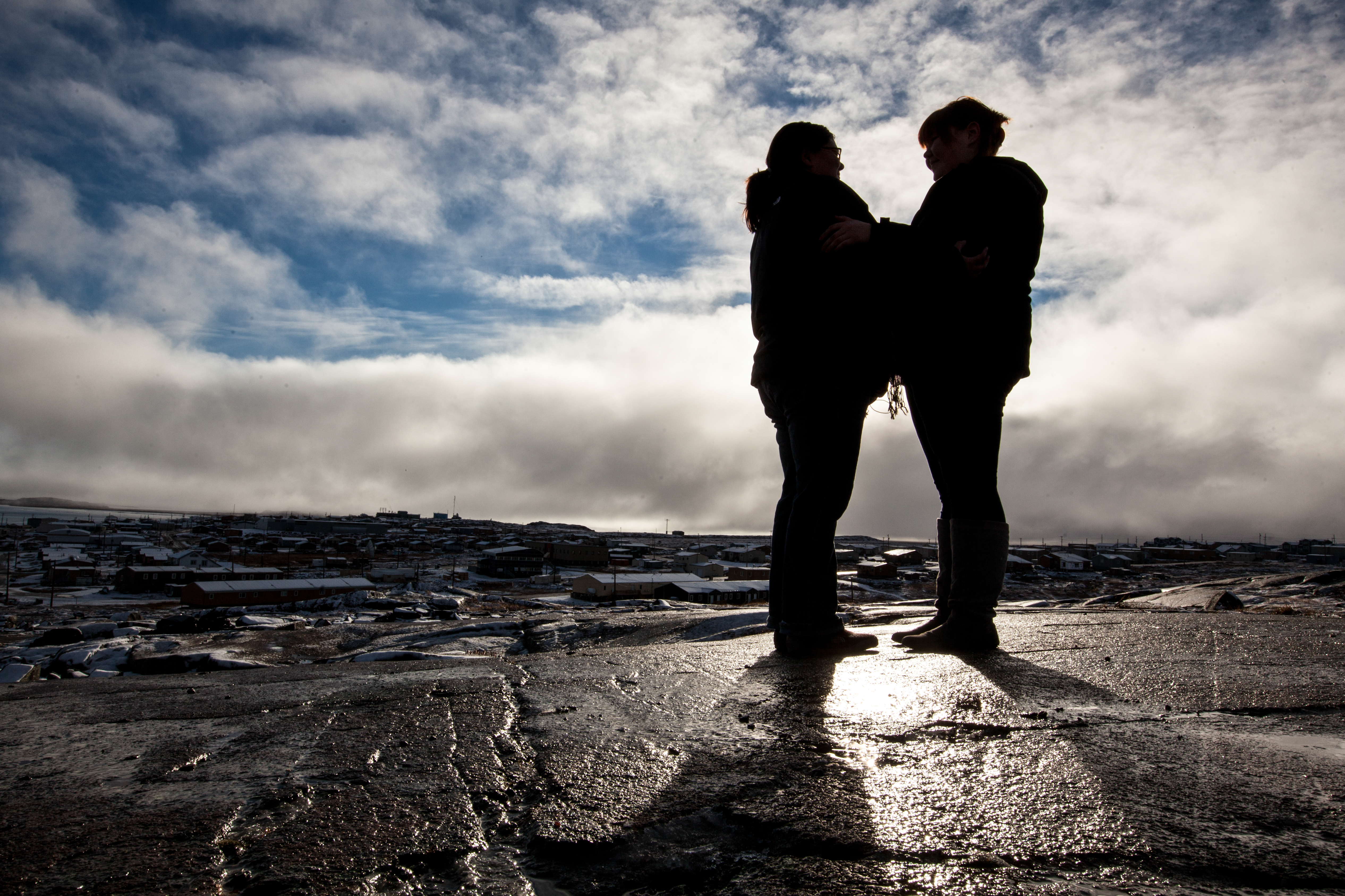 Two people in the foreground of a community in Canada’s North