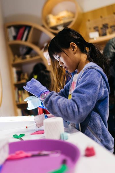 A young girl makes a mix to grow a new microbe material in Making with Microbes at The Tech Interactive. The bioengineering activity is one of three experiences that empower people to use biology as a technology. 