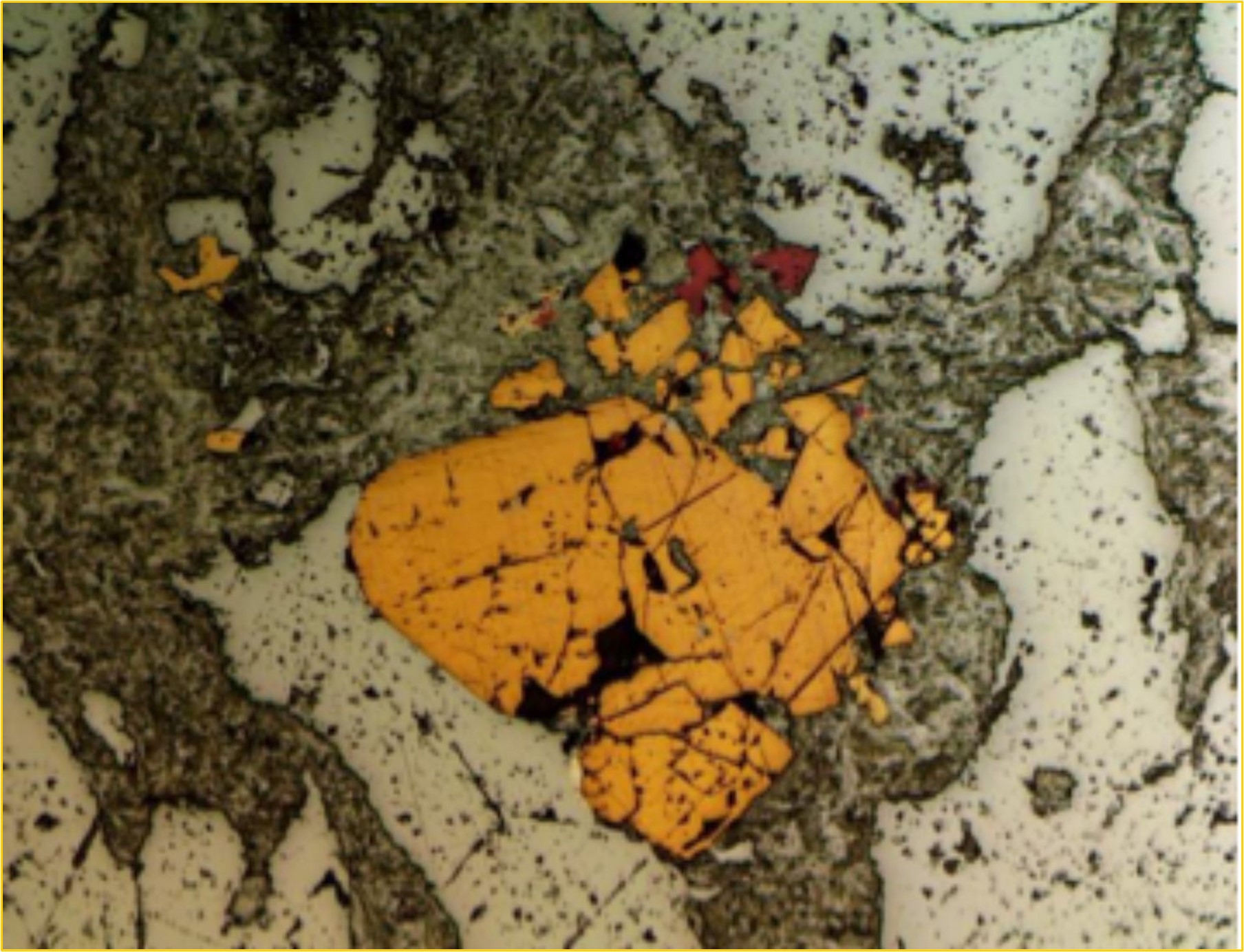 Drill core 20MT-002 showing a  grain of pyrite and arsenian pyrite (dark yellow), chalcopyrite (red), and tetrahedrite (light yellow). These sulphides are within a groundmass of fine-grained phengitic muscovite, chlorite, and albite. The field of view is 2 millimetres.