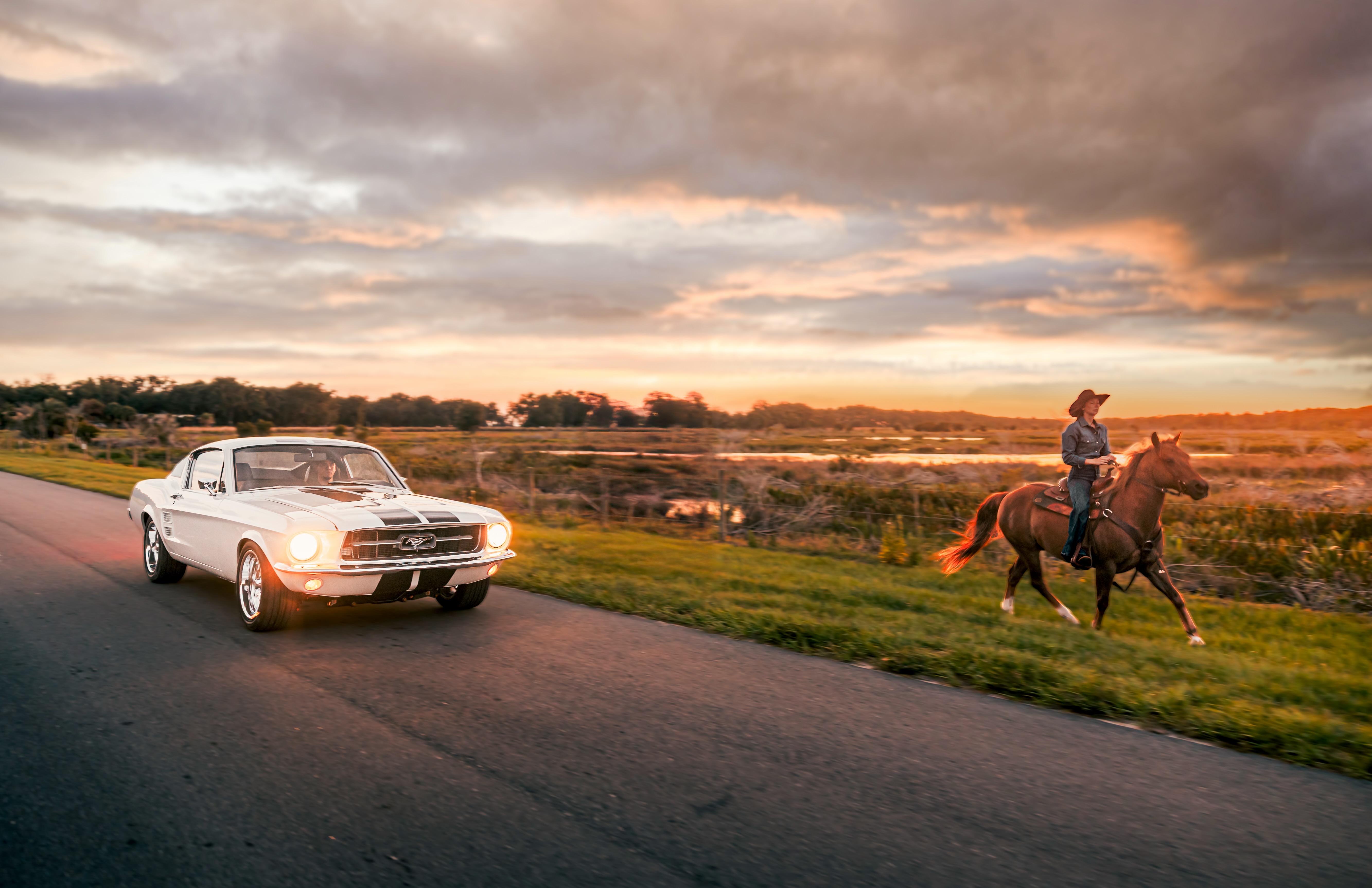 ECD’s first fully built custom 1967 Mustang Fastback drives beside a horseback rider at sunset, blending modern power with American heritage.