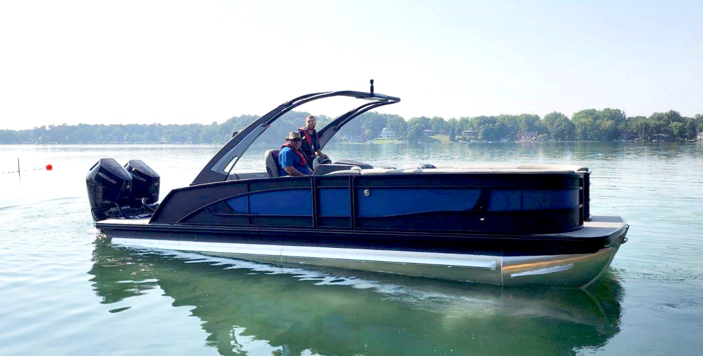 Two men sitting in a Barletta pontoon boat on a lake