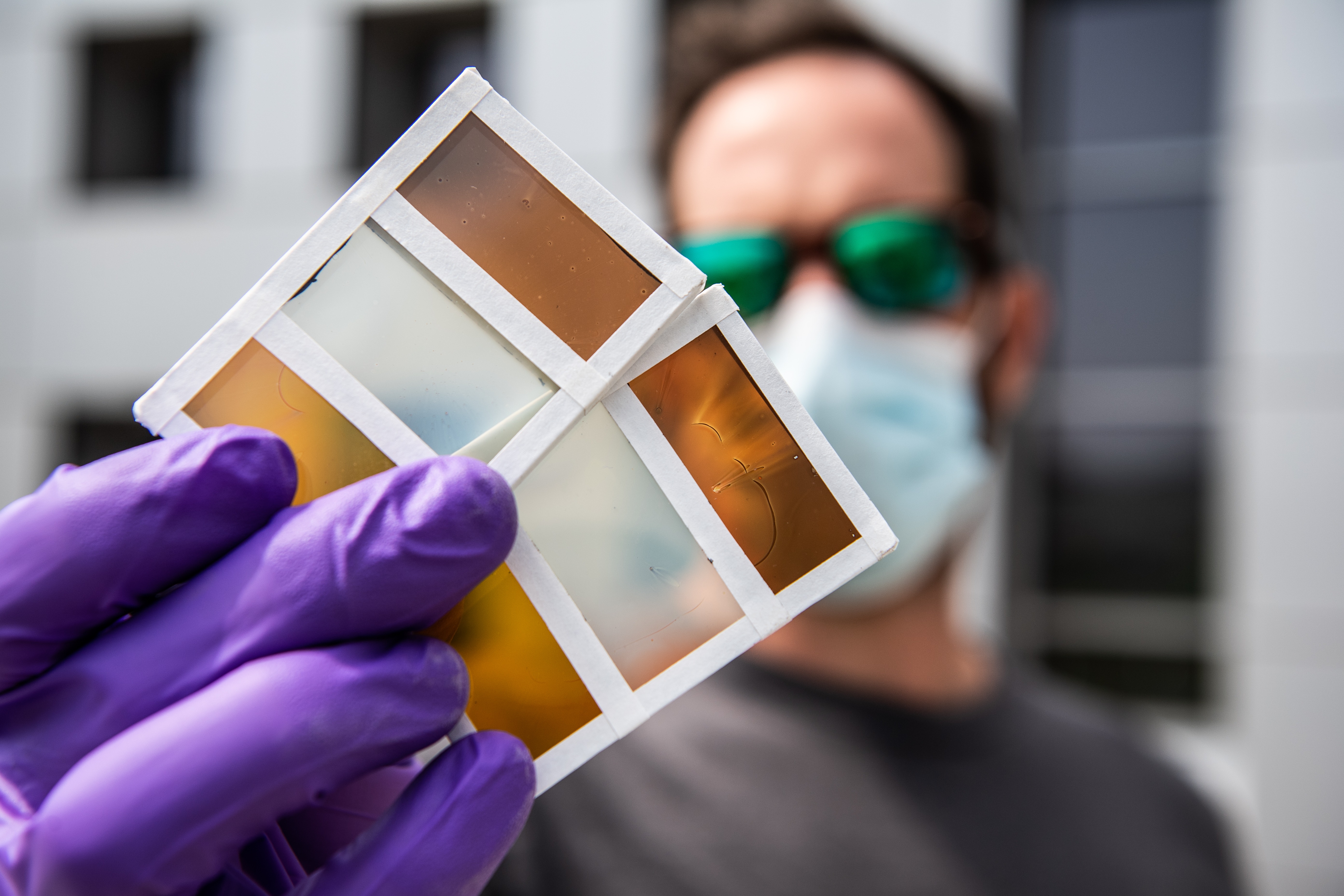 NREL researcher Lance Wheeler holds a perovskite window prototype that can switch between a variety of colors. Photo by Dennis Schroeder, NREL
