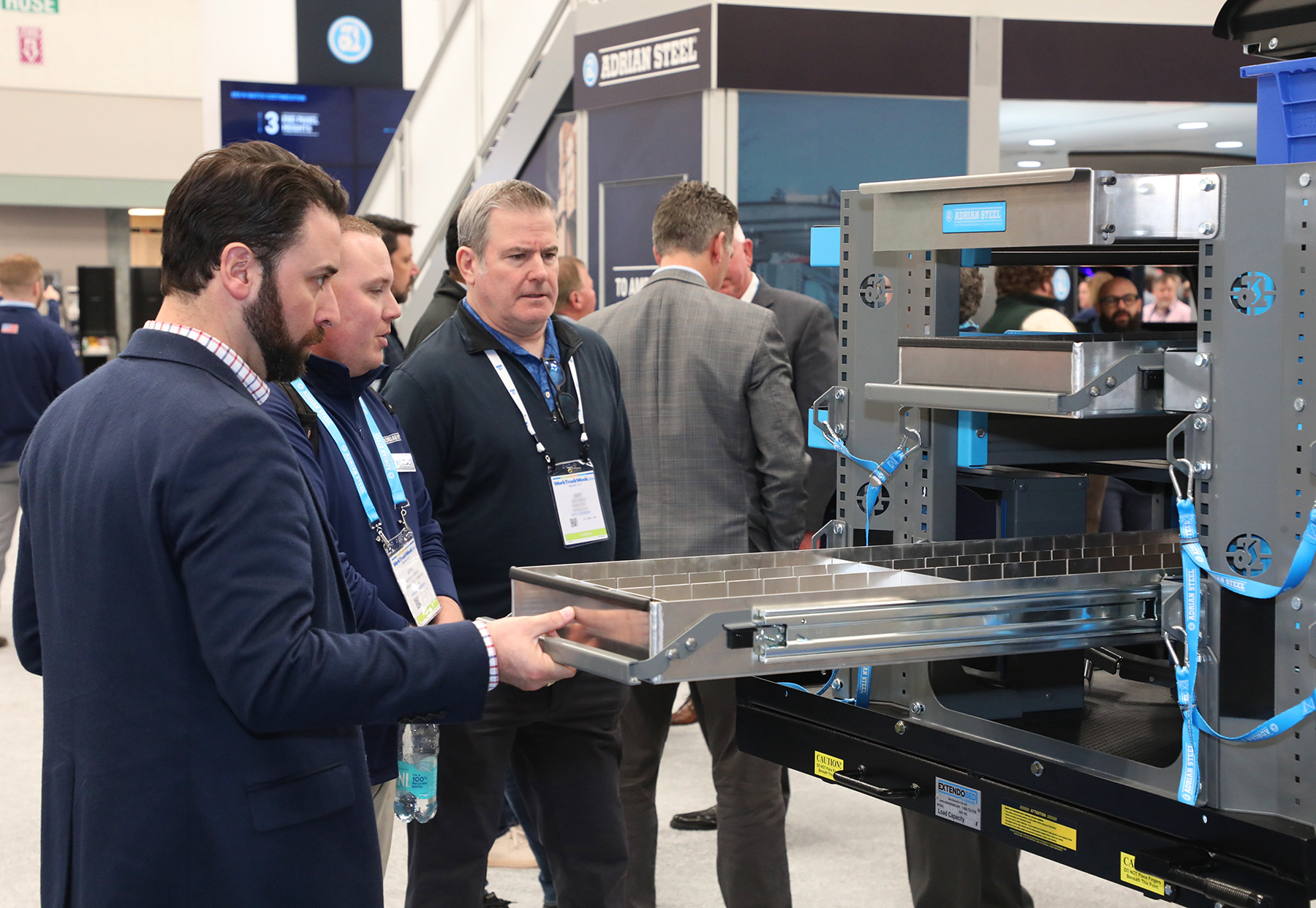 A man pulls out a drawer from an Adrian commercial vehicle modular storage system on display at Work Truck Week.