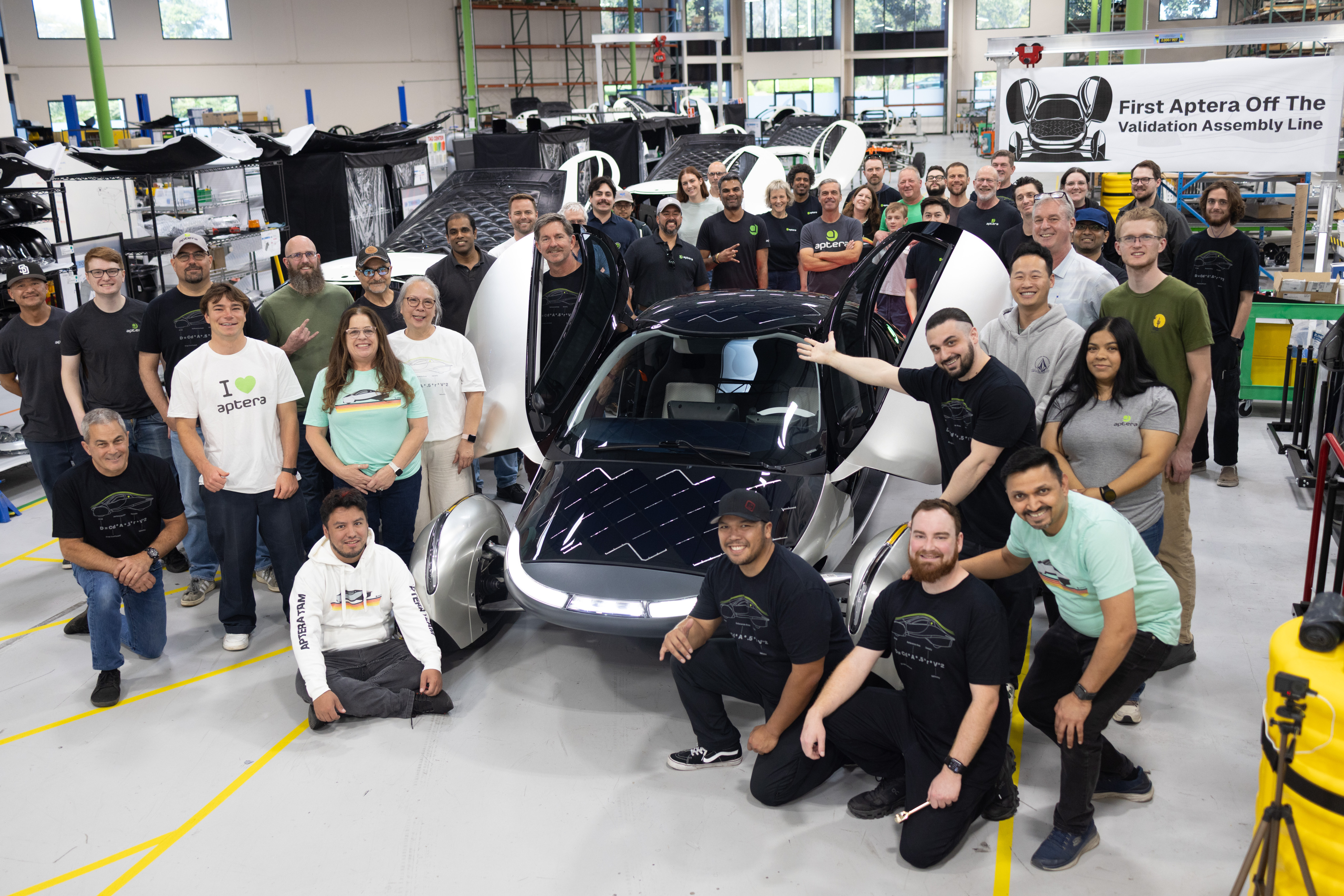 Aptera team members stand proudly around the first solar electric vehicle to roll off the low-volume validation line.