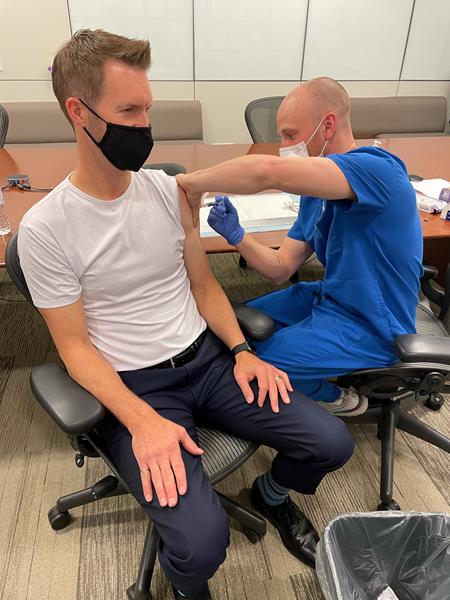 Chad Leier, president of Fluid Energy Group, receives flu shot from Numi.