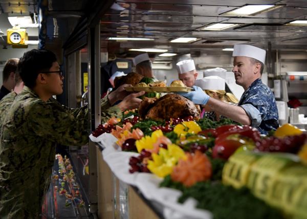 Thanksgiving, 181122-N-RI884-0236: Capt. Colby Howard (right), commanding officer of the amphibious assault ship USS Wasp (LHD 1), serves a traditional Thanksgiving meal to sailors during a celebration aboard the ship forward deployed to Sasebo, Japan, Nov. 22, 2018. Each year, DLA Troop Support Subsistence supply chain employees ensure service members around the world get to enjoy a traditional Thanksgiving meal. (U.S. Navy photo by Mass Communication Specialist 1st Class Daniel Barker)