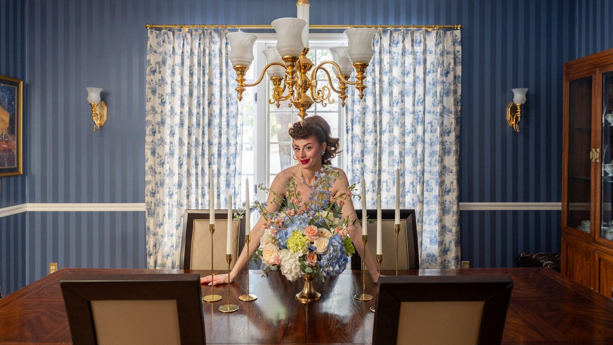 Ms. Maverick Muse standing behind a dining table adorned, in front of a window dressed with TWOPAGES Print Linen Cotton Drapery in Toile Galactica MM-