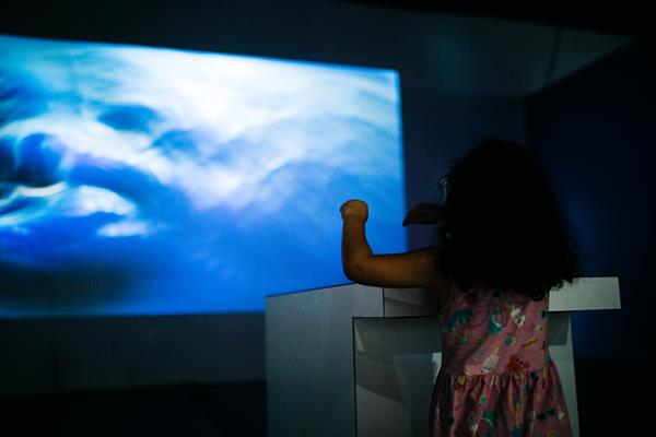 A young girl manipulates "water" in midair as part of Studio TISH's instillation Resonance at The Tech Interactive in San Jose, CA. 