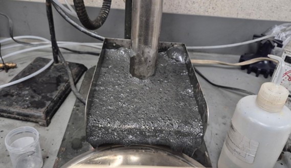 Preliminary metallurgical test of composite material from RPM zone at Pipestone XL project, picture showing the rougher flotation stage. The metallic surface visible on-top of liquid within a bench scale flotation cell is awaruite particles attaching to the surface of bubbles and floating to the top to be collected and cleaned in a multi-stage process isolating and concentrating the awaruite nickel–iron-cobalt alloy metal. 