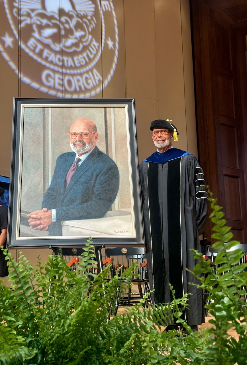 Dr. Lomax posing with his portrait which is being displayed in the Morehouse International Hall of Honor