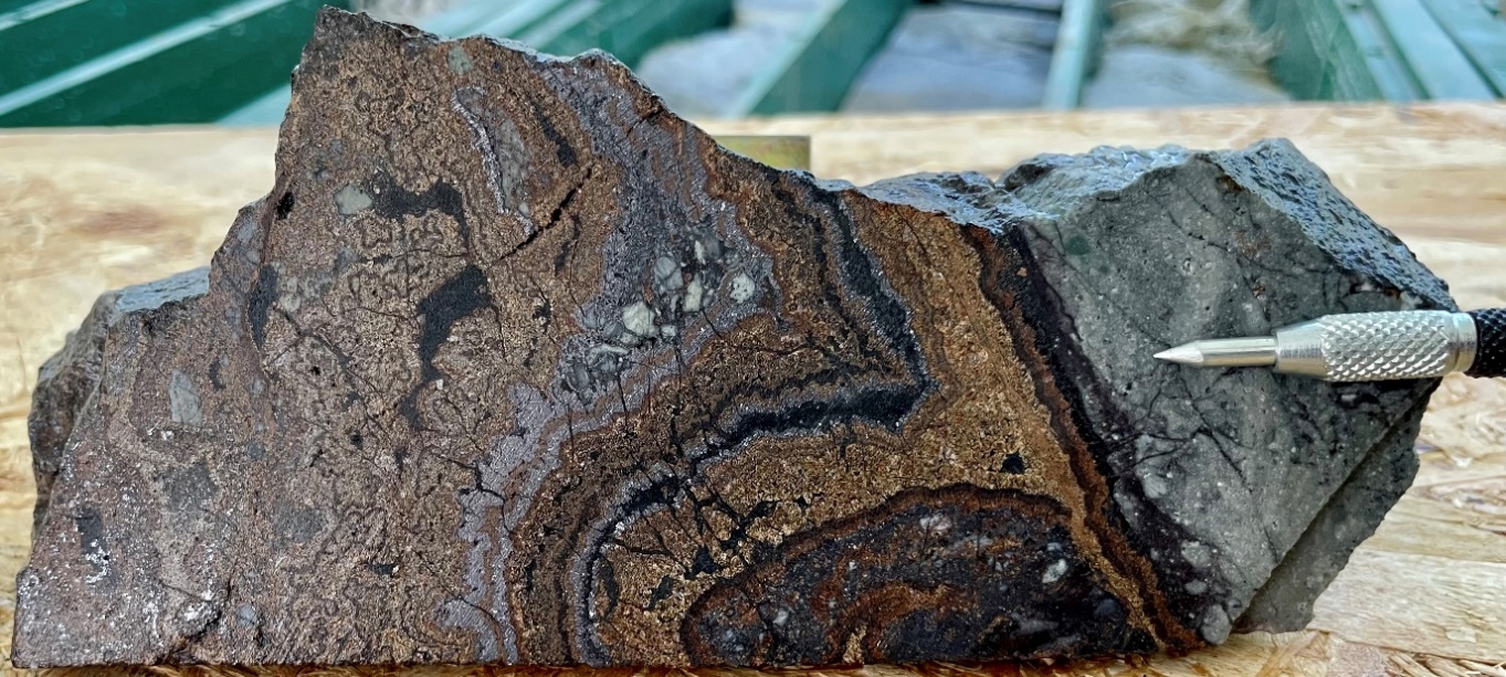 Photograph of 45.35 – 45.50 m in drillhole CMVDD002. Orange, brown colloform-crustiform banded sphalerite and galena can be observed with weakly brecciated lower vein contact with andesitic tuff.