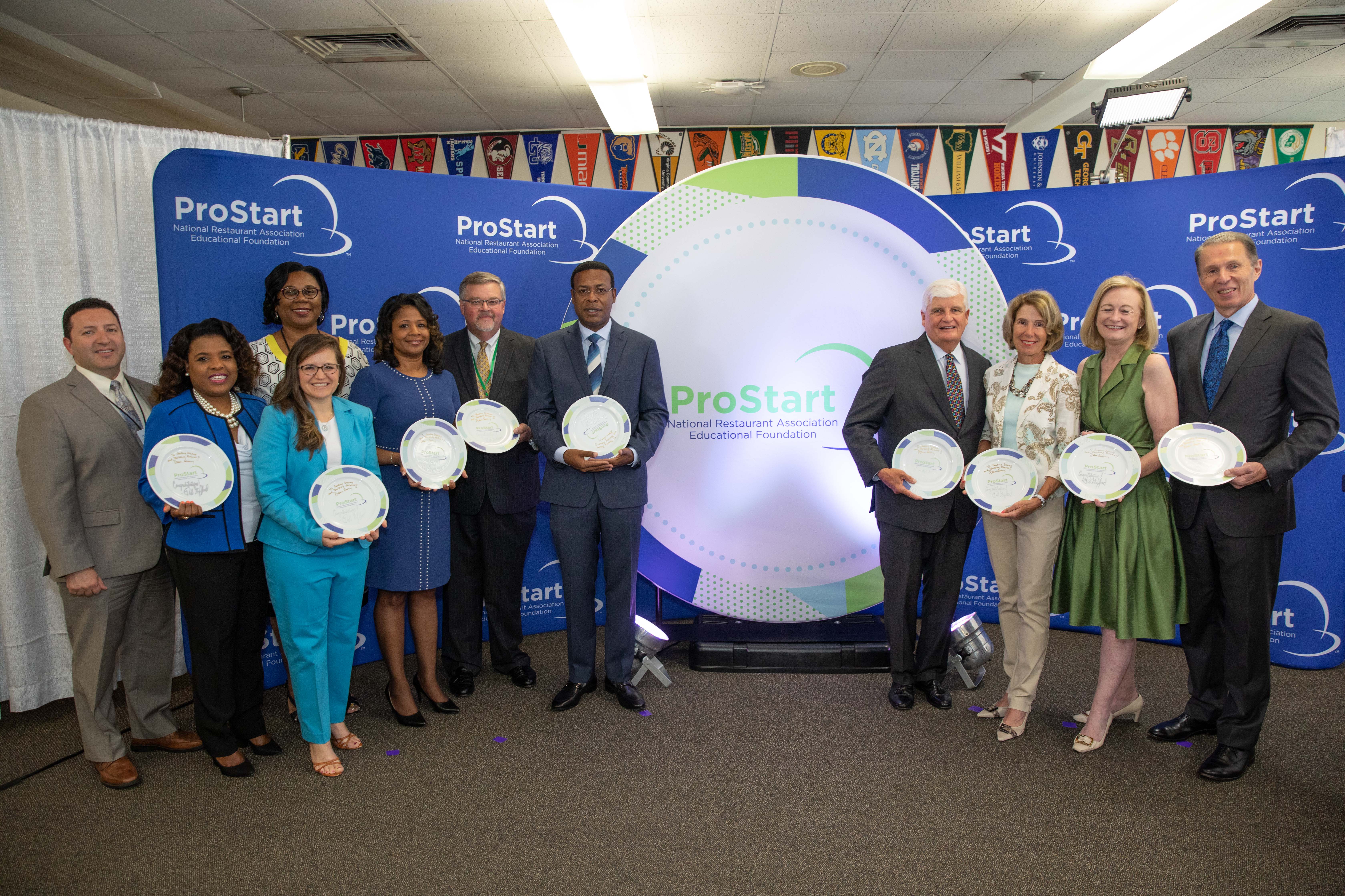 NPS dignitaries; Dr. Sharon Byrdsong, Superintendent of Norfolk Public Schools; Dr. Noëlle M. Gabriel, Norfolk Public Schools Board Chair; Eric Terry, Virginia Restaurant, Lodging & Travel Association President and CEO; the Honorable Kenny Alexander, Mayor of Norfolk; Hu and Evie Odom; Dawn Sweeney, President and CEO of the National Restaurant Association and CEO of the NRAEF; and Rob Gifford, President of the NRAEF.